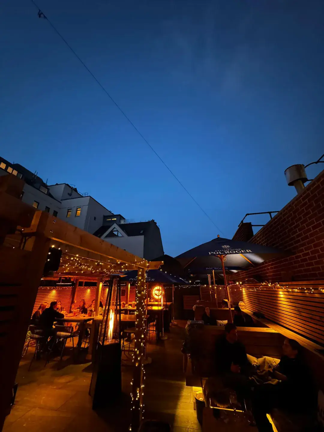 The Wildes garden terrace at twilight, lit with festoon lights