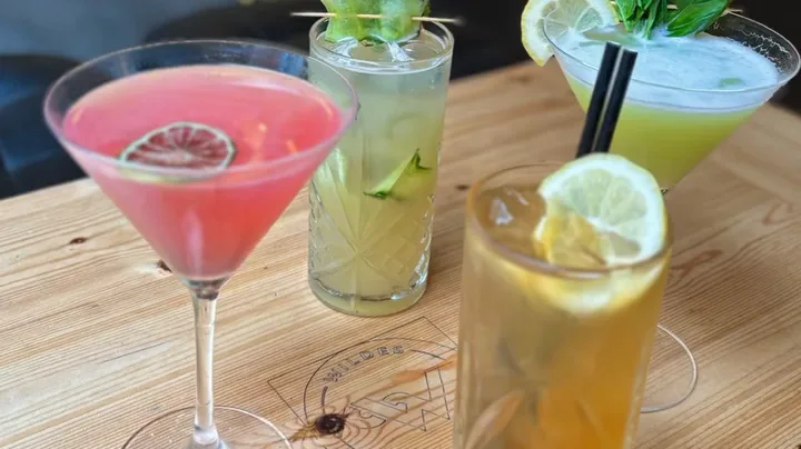 Four Wildes cocktails on a wooden table branded with the bar's logo