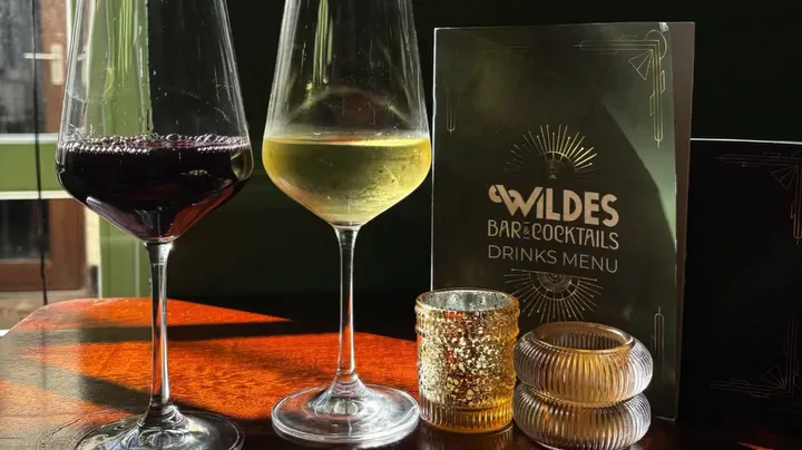 A glass of red and a glass of white beside the Wildes drinks menu